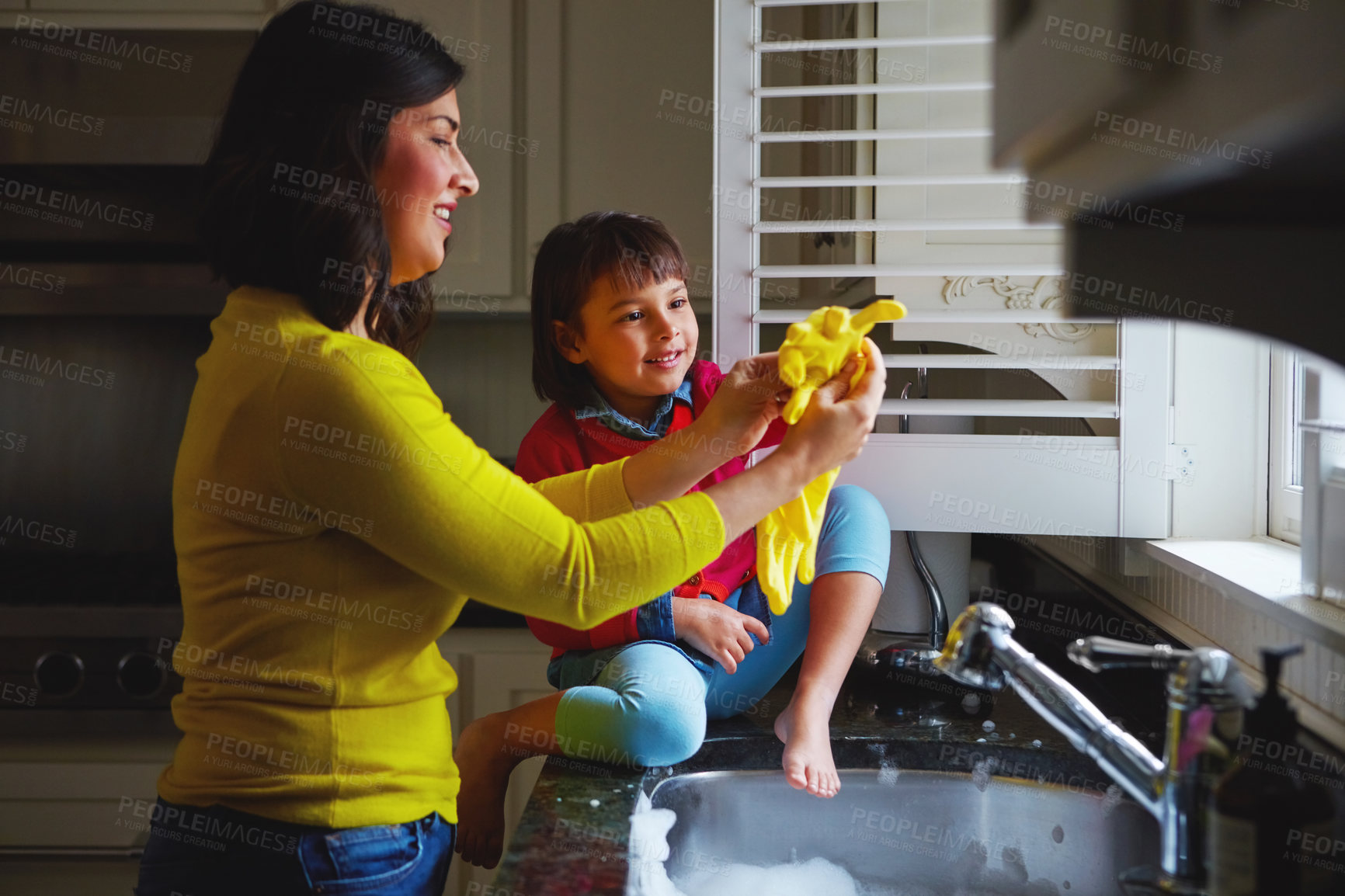 Buy stock photo Shot of a young mother and her daughter playing by the kitchen sink