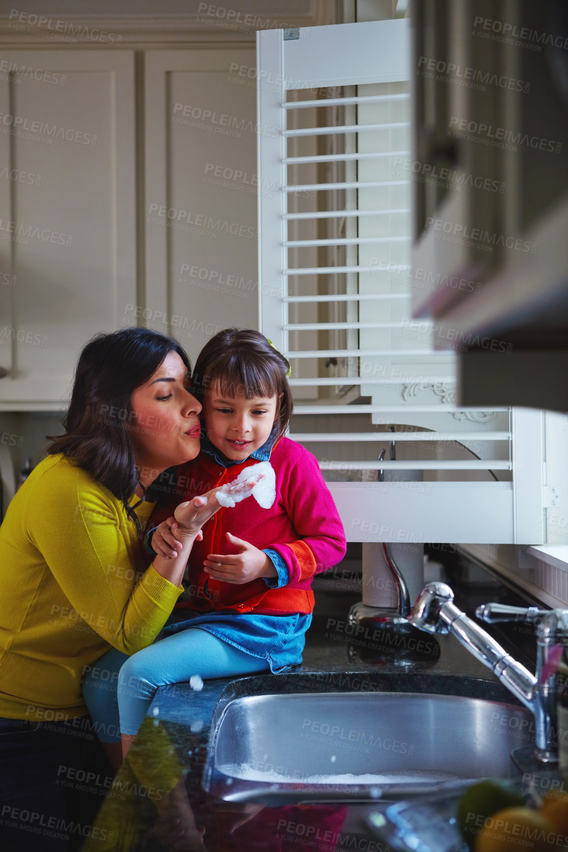 Buy stock photo Shot of a young mother and her daughter playing by the kitchen sink