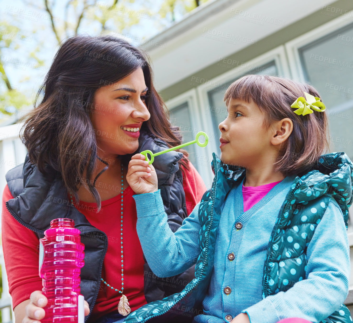 Buy stock photo Cropped shot of a mother watching her daughter blow bubbles outside