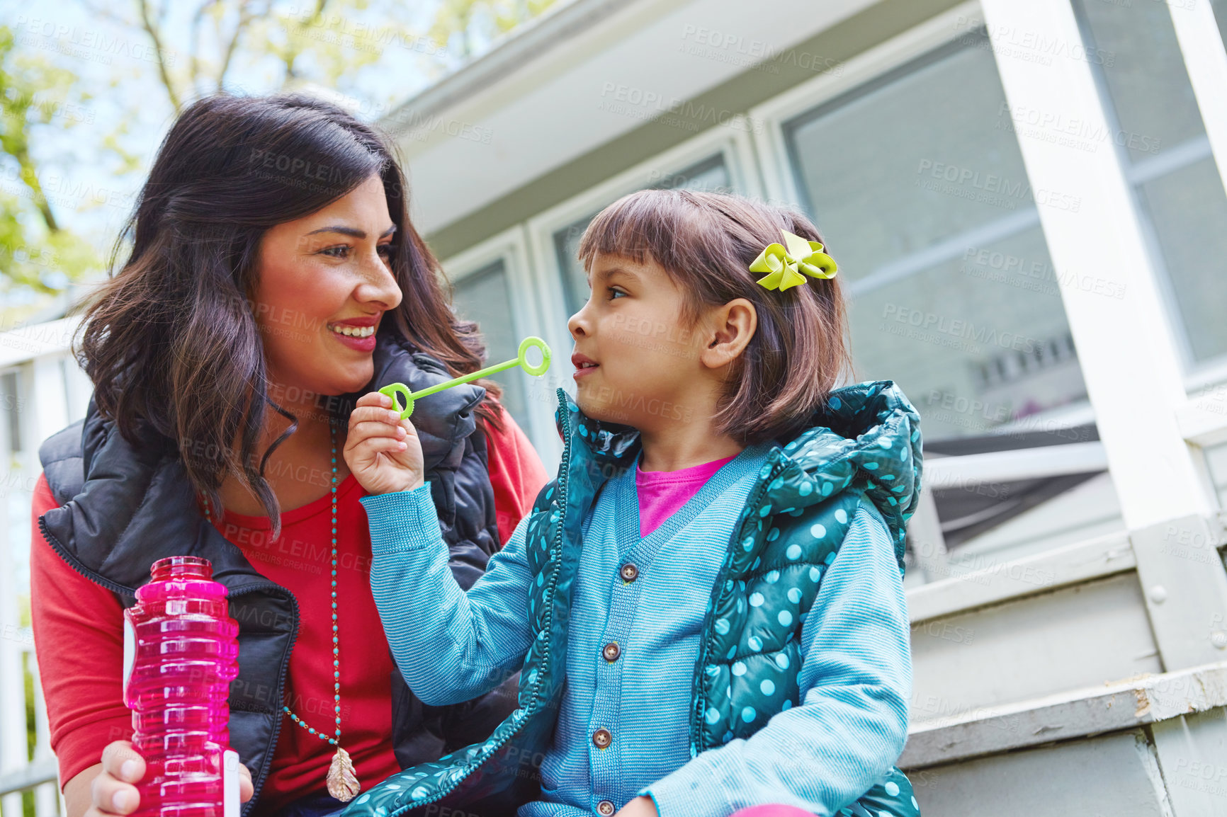 Buy stock photo Cropped shot of a mother watching her daughter blow bubbles outside