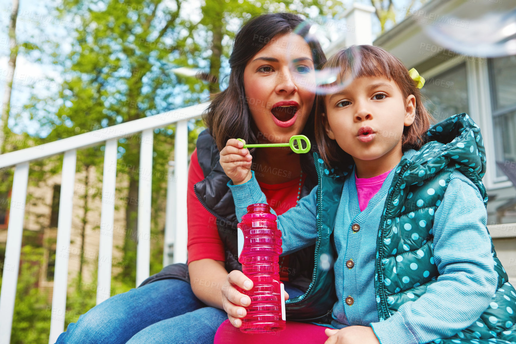 Buy stock photo Cropped shot of a mother watching her daughter blow bubbles outside