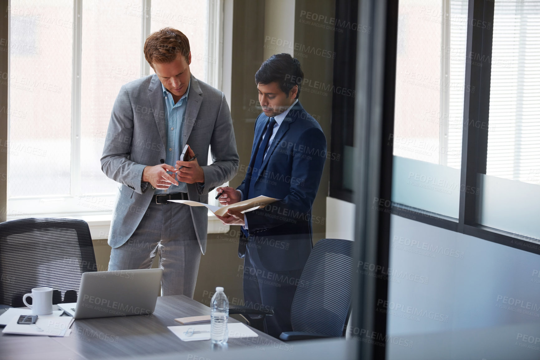 Buy stock photo Cropped shot of businessmen looking at paperwork in their office