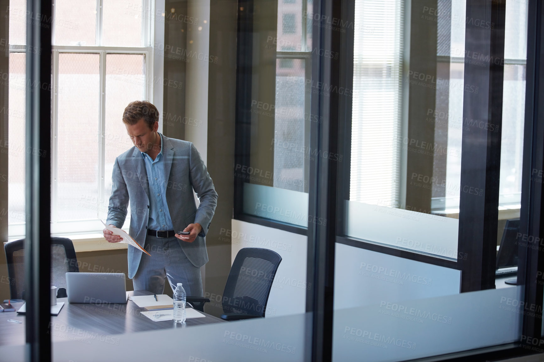 Buy stock photo Cropped shot of a businessman looking at paperwork in his office