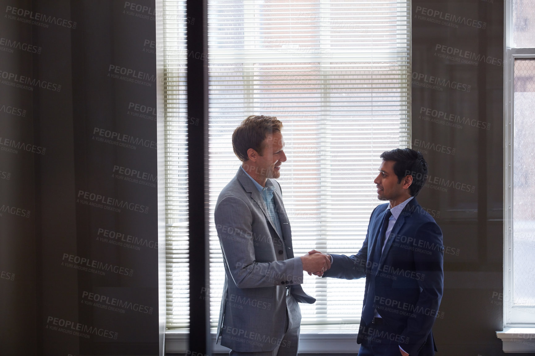 Buy stock photo Cropped shot of two businessmen shaking hands in the office