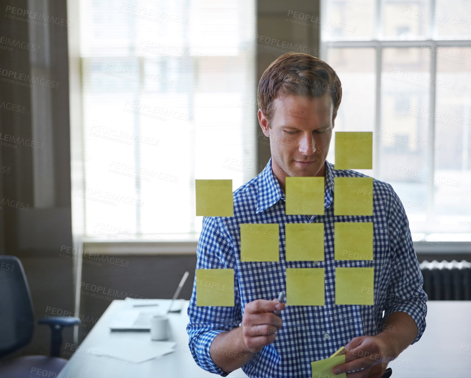 Buy stock photo Cropped shot of a handsome businessman arranging adhesive notes on a glass pane