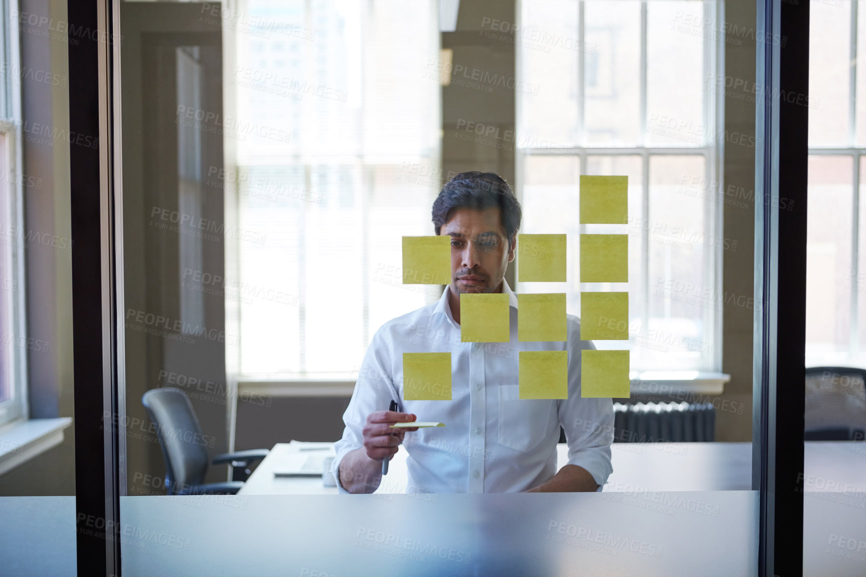 Buy stock photo Cropped shot of a handsome middle eastern businessman arranging adhesive notes on a glass pane