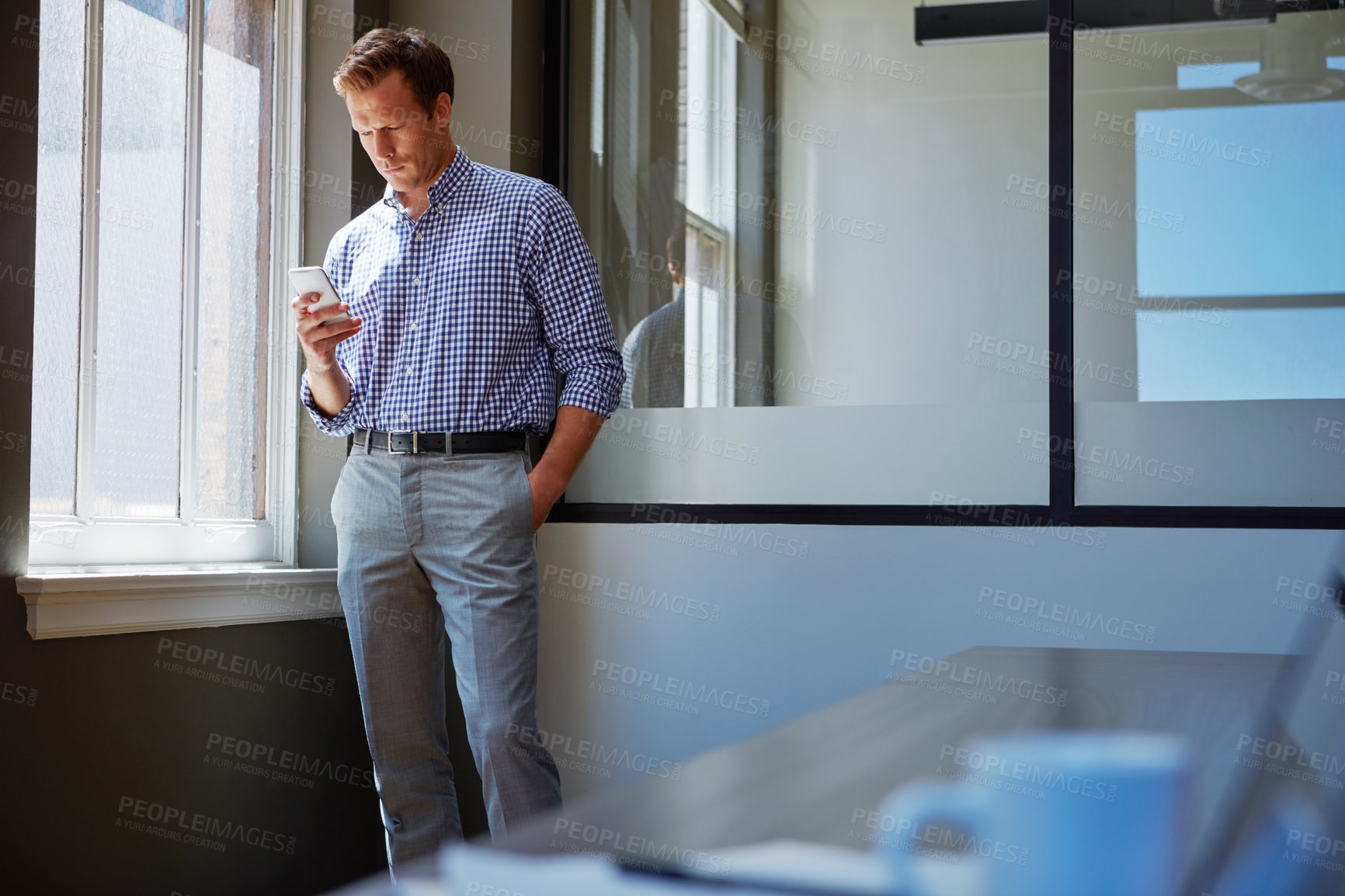 Buy stock photo Shot of a businessman working on his smartphone in the office