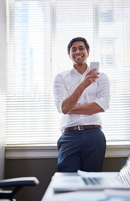 Buy stock photo Shot of a businessman working on his smartphone in the office