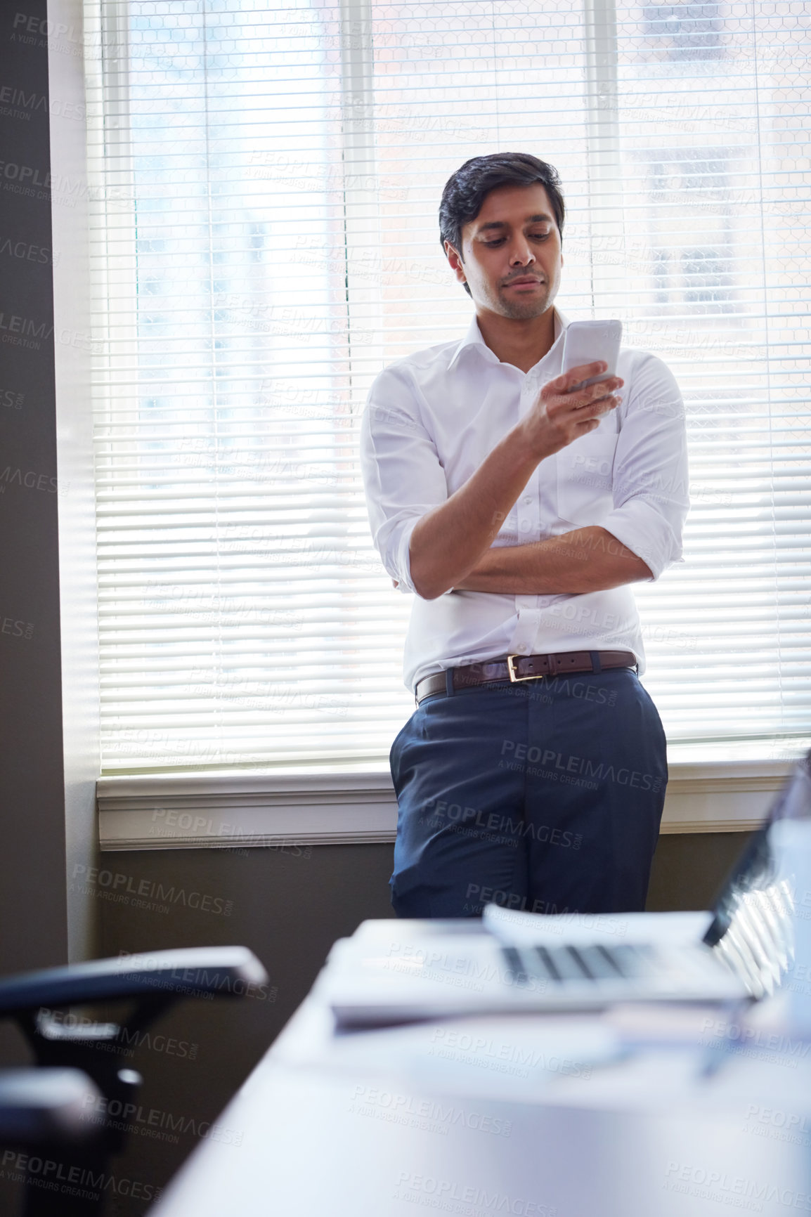 Buy stock photo Shot of a businessman working on his smartphone in the office