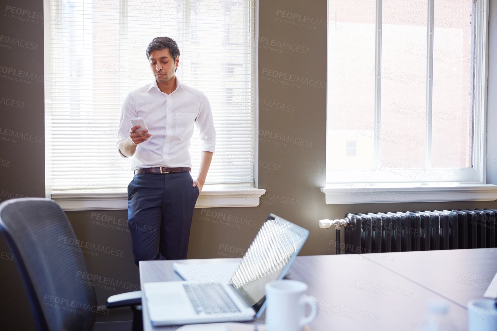 Buy stock photo Shot of a businessman working on his smartphone in the office