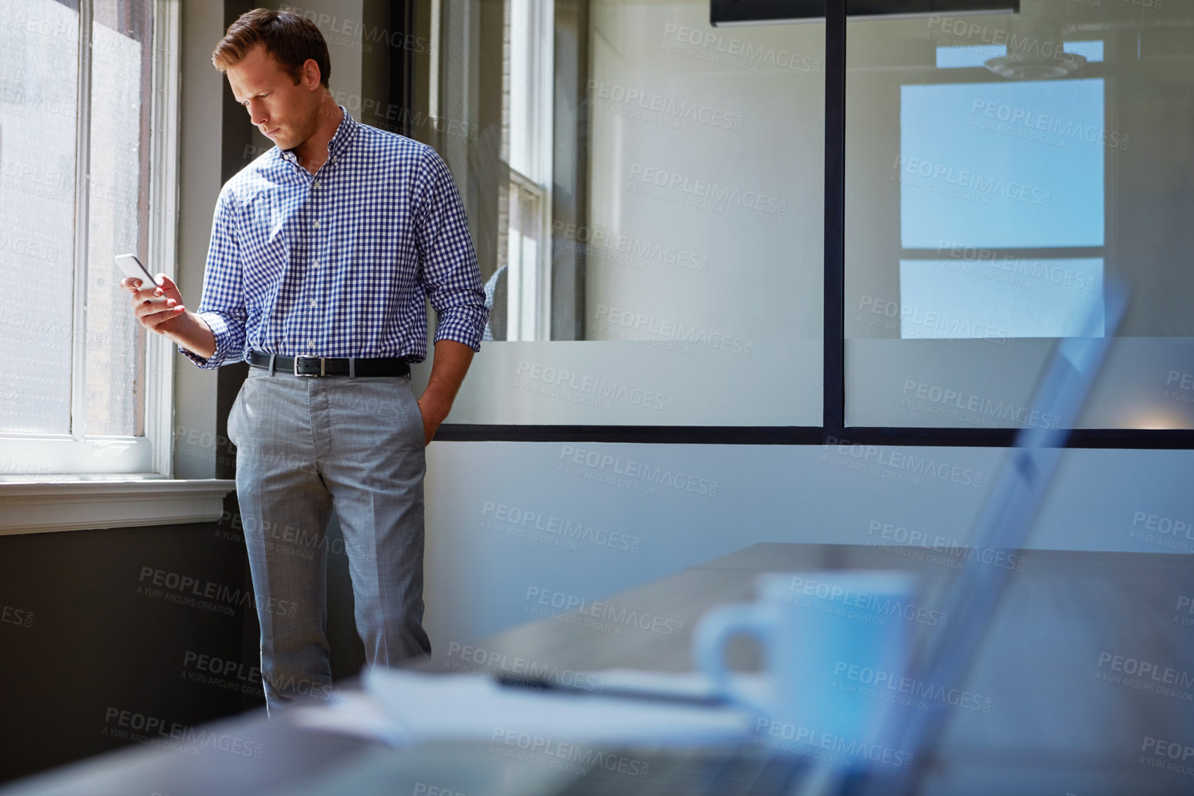 Buy stock photo Shot of a businessman working on his smartphone in the office