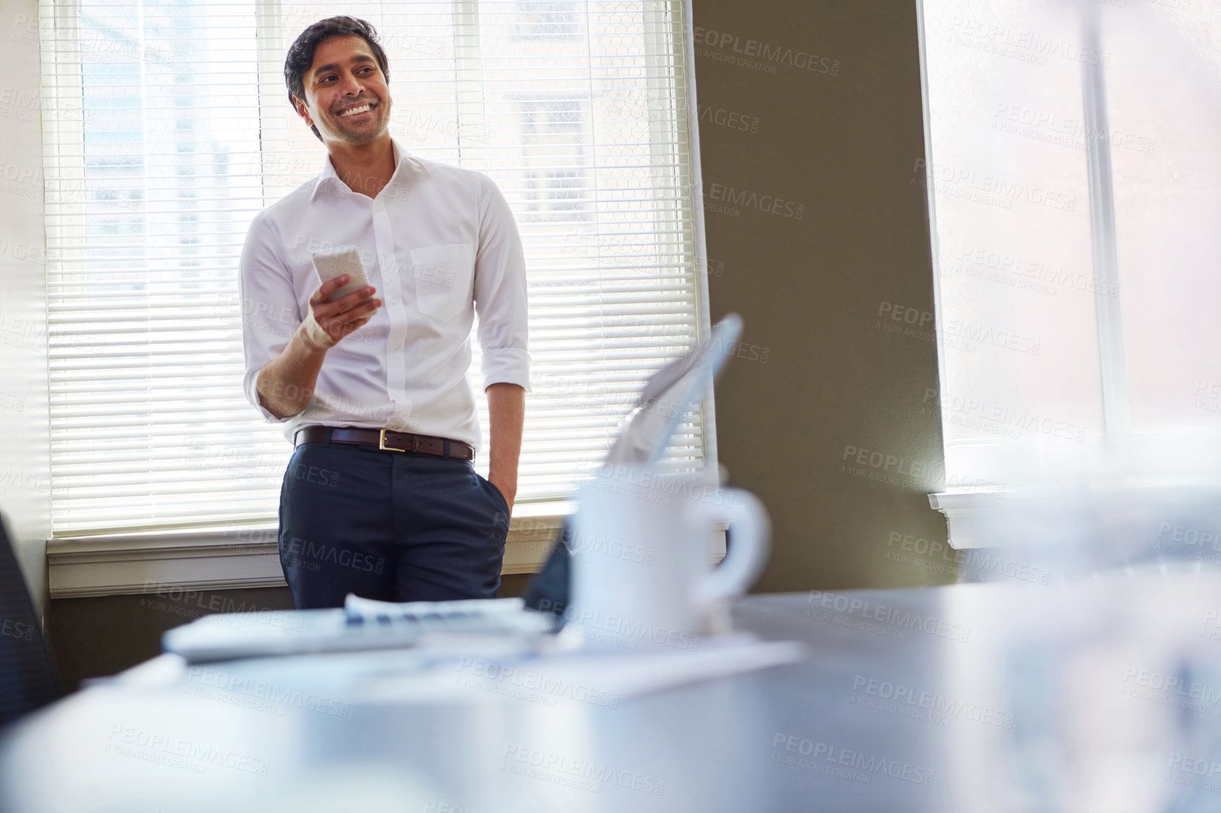 Buy stock photo Shot of a businessman working on his smartphone in the office