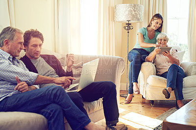 Buy stock photo Shot of a man and woman showing their elderly parents how to use wireless technology at home