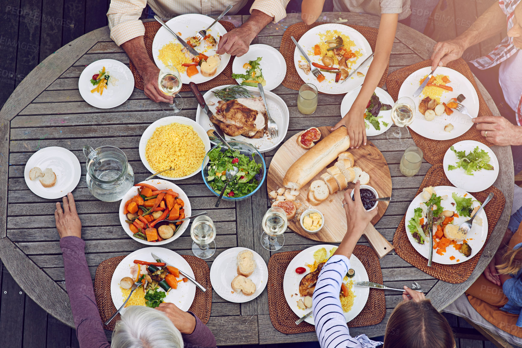 Buy stock photo Hands, family and children at lunch table for bonding, thanksgiving celebration and eating on patio. Men, women and kids at outdoor picnic on terrace with food, fun and sharing together from above