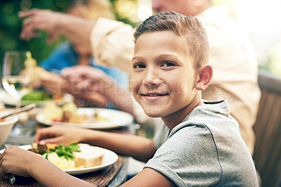 Buy stock photo Portrait of a happy little boy enjoying an outdoor lunch with his family