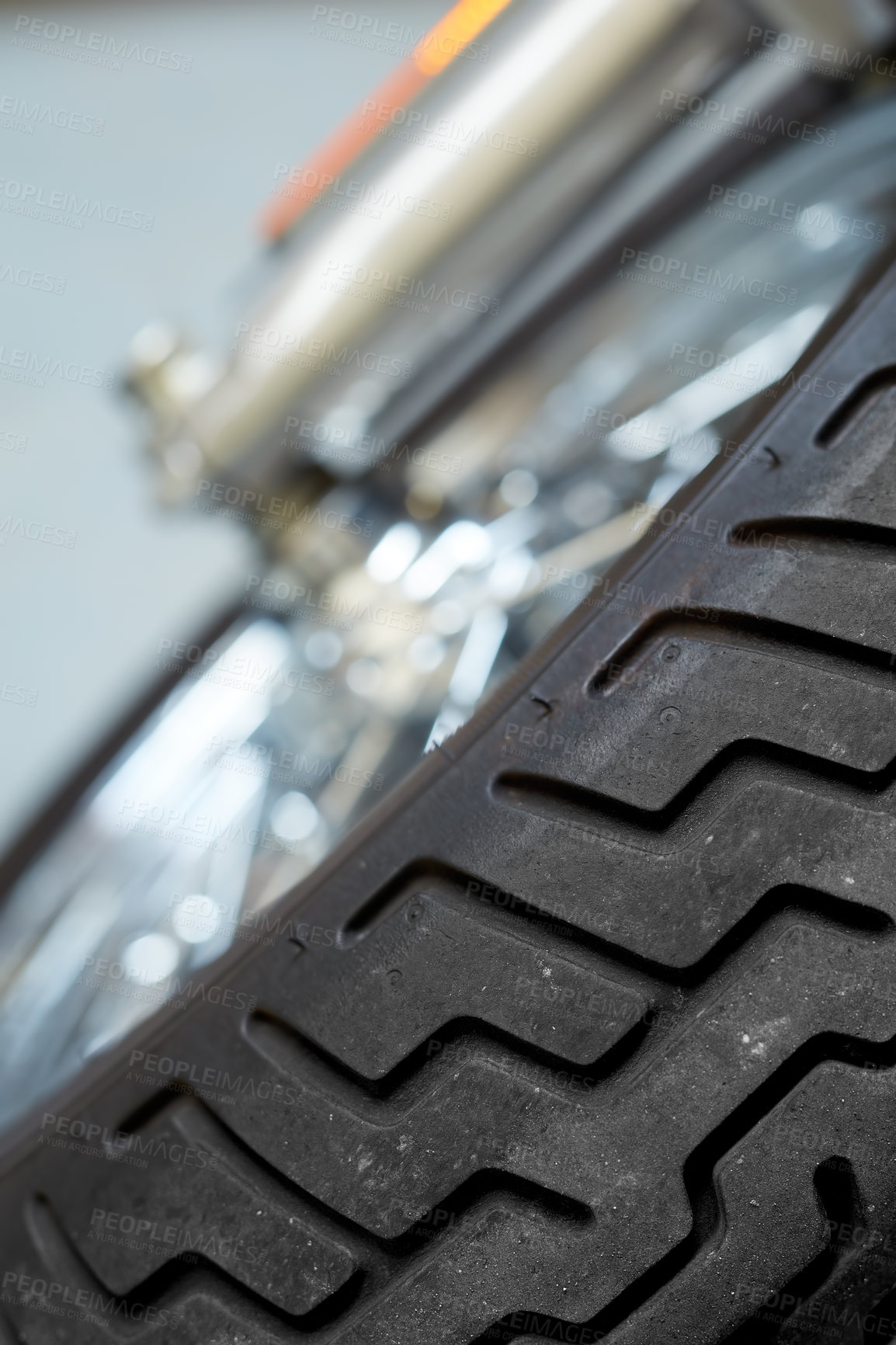 Buy stock photo Closeup tilted view of a motorbike tire. Tires designed for custom modern sports bike. Suspension on classic motorcycle front wheel. Maintenance on vintage shock absorber and reflector on chrome body