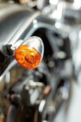 Buy stock photo Closeup rear view of a taillight on a motorbike. Orange turning light on a blurred black vintage motorcycle. One modern chrome transportation vehicle. Maintenance on a shiny classic retro custom bike