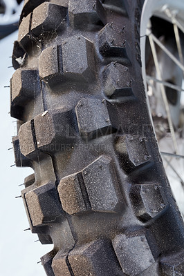 Buy stock photo Closeup of a used motorcycle wheel. Detail of tire patterns on a motor bike. A well travelled tyre wheel with road dirt. Rear view of black knobby rubber bicycle wheel a repair or maintenance concept