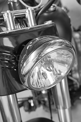 Buy stock photo Closeup front view of a head light on a motorbike. A monochrome vintage motorcycle in black and white. One modern silver chrome transportation vehicle. Maintenance on a classic retro custom bike