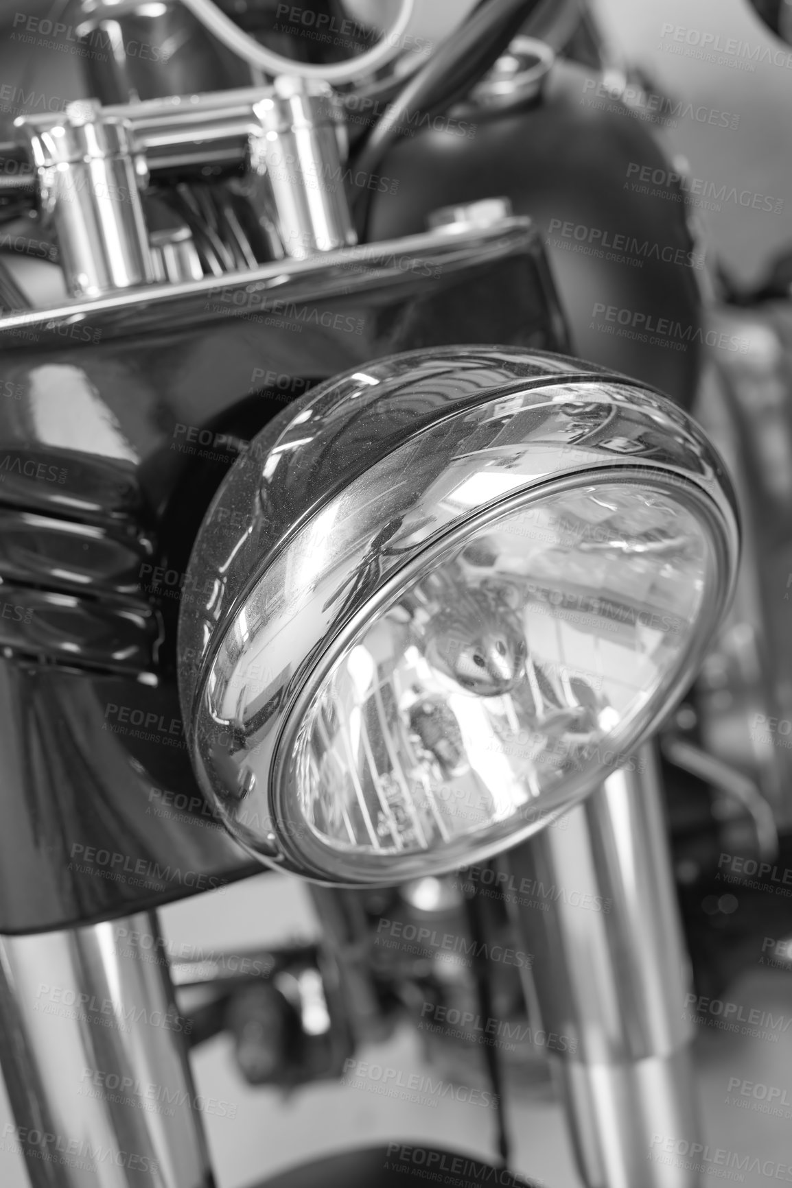 Buy stock photo Closeup front view of a head light on a motorbike. A monochrome vintage motorcycle in black and white. One modern silver chrome transportation vehicle. Maintenance on a classic retro custom bike