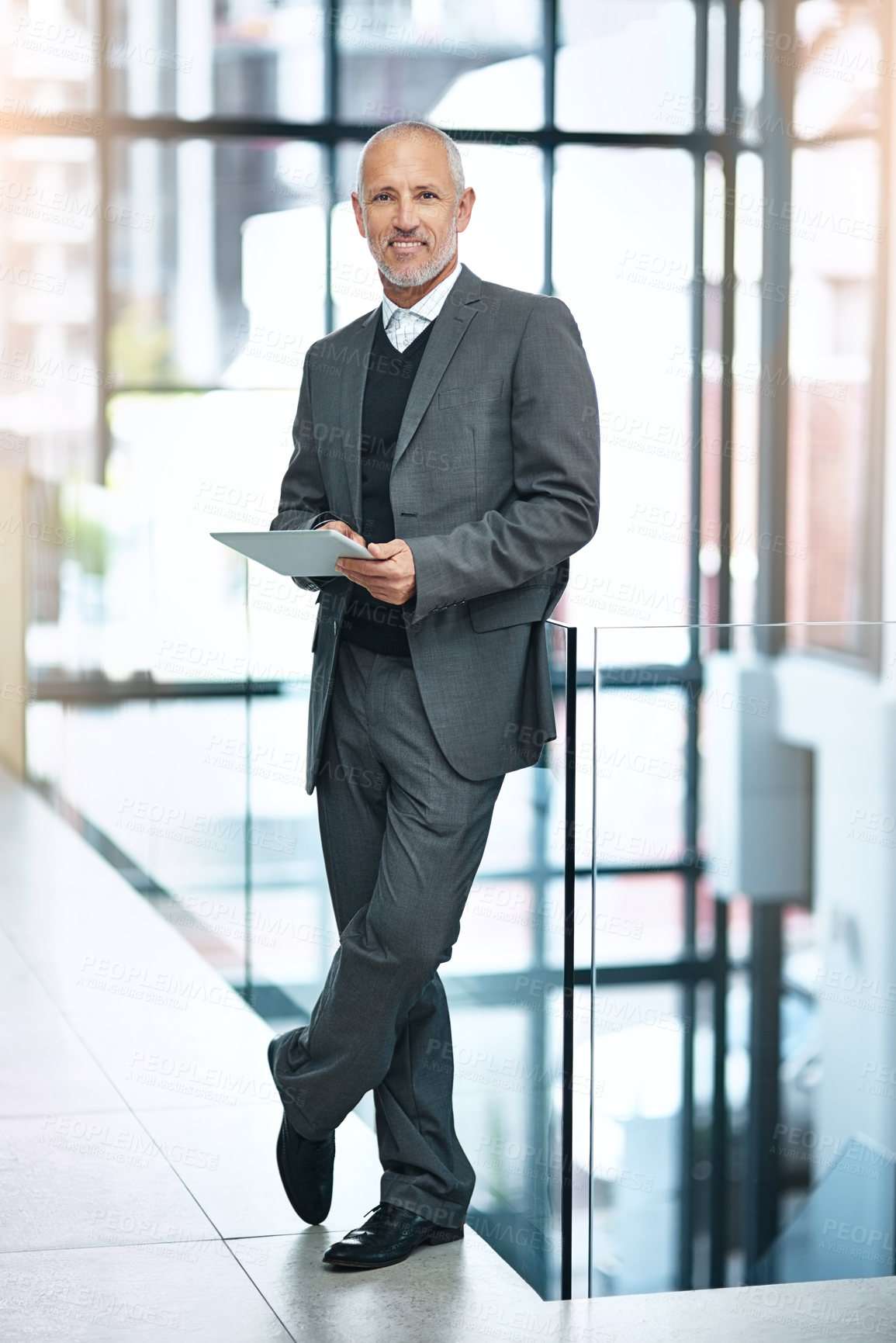Buy stock photo Shot of a mature businessman using his digital tablet at the office
