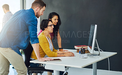 Buy stock photo Cropped shot of a group of colleagues working together on a computer in a modern office