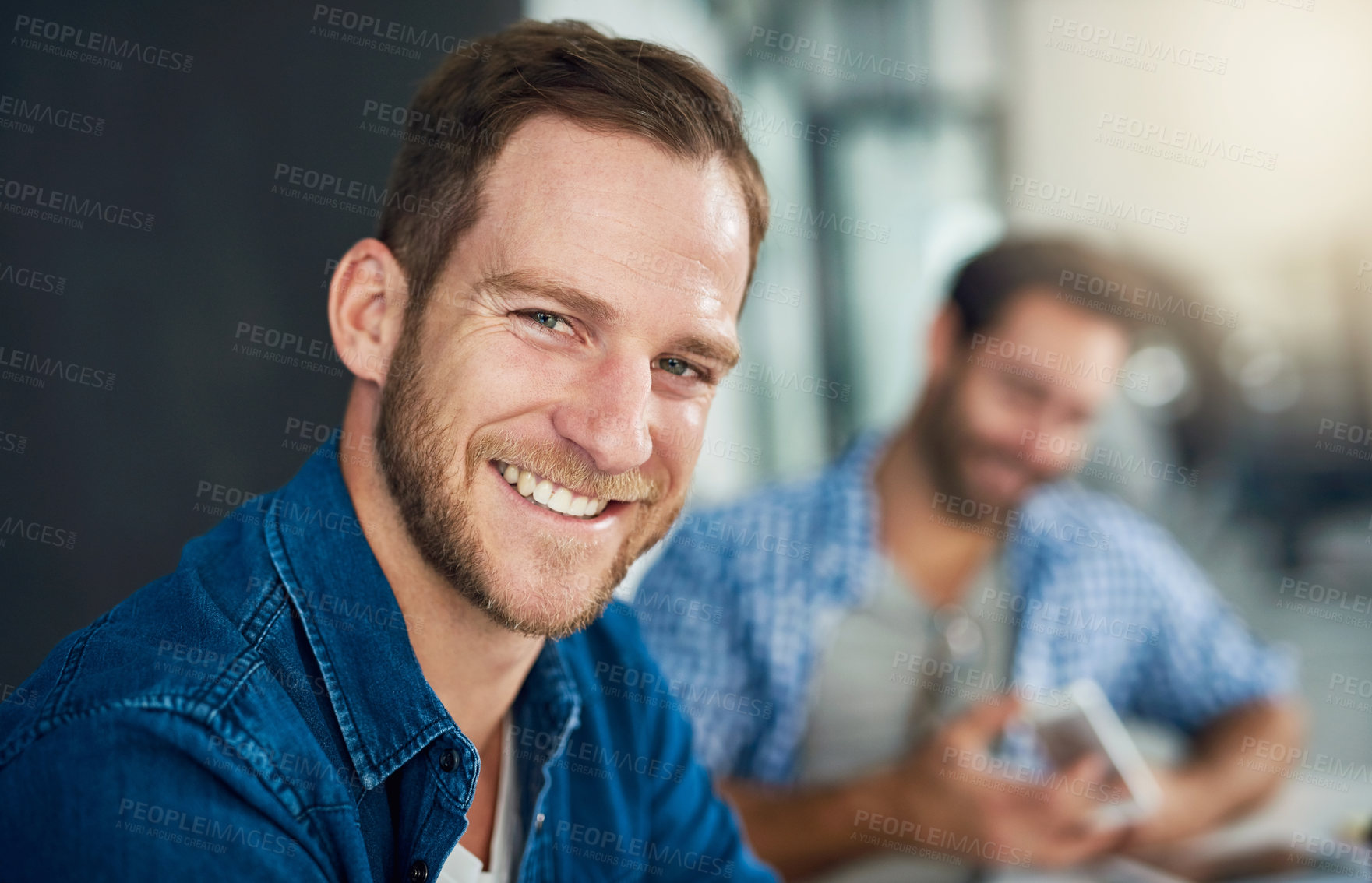 Buy stock photo Portrait of a young businessman sitting in a modern office with colleagues