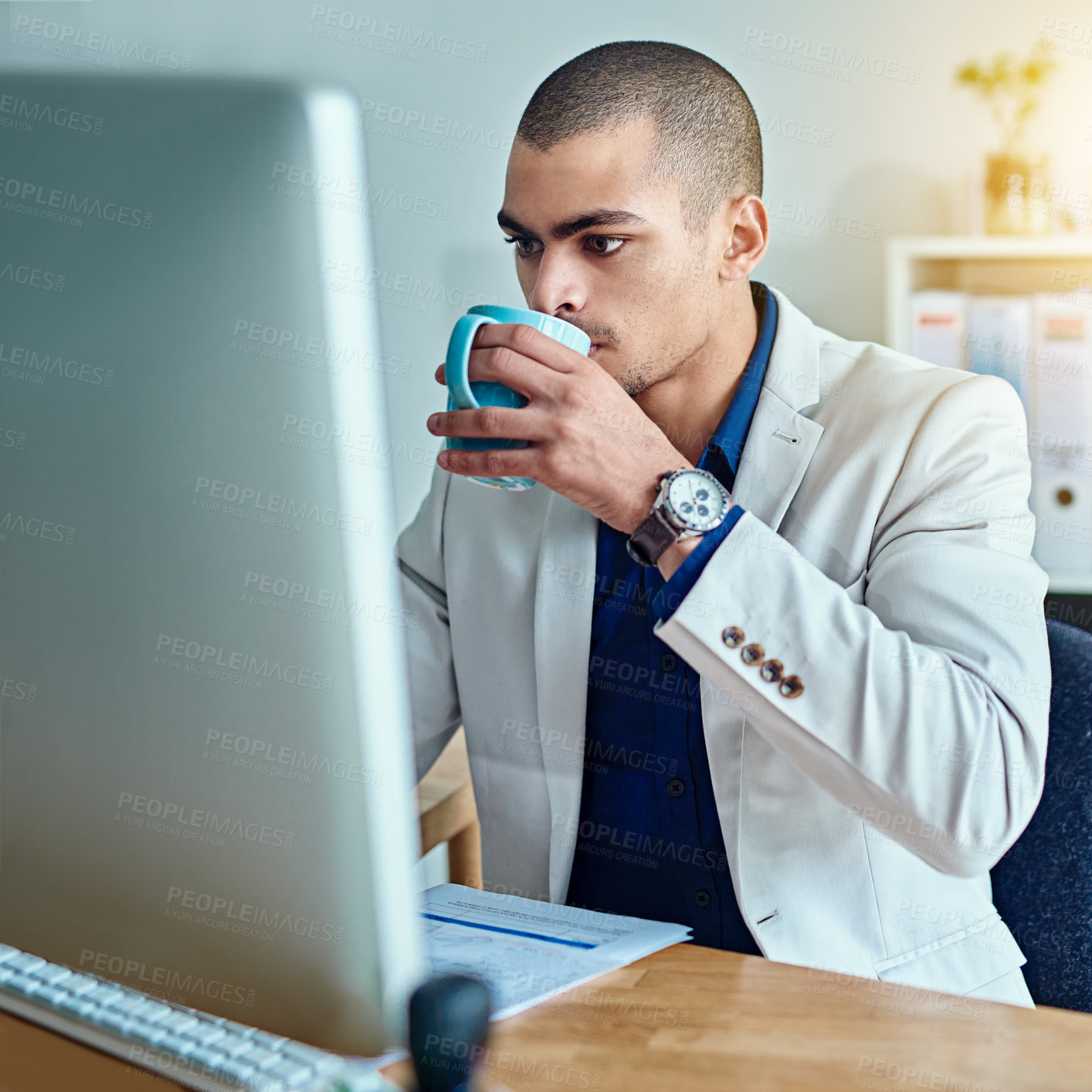 Buy stock photo Cropped shot of a young businessman drinking coffee while working in an office