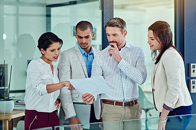 Buy stock photo Shot of a group of coworkers talking over some paperwork in an office