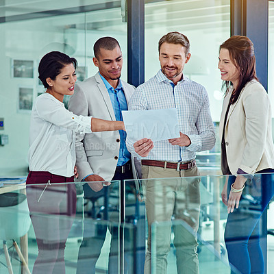 Buy stock photo Shot of a group of coworkers talking over some paperwork in an office
