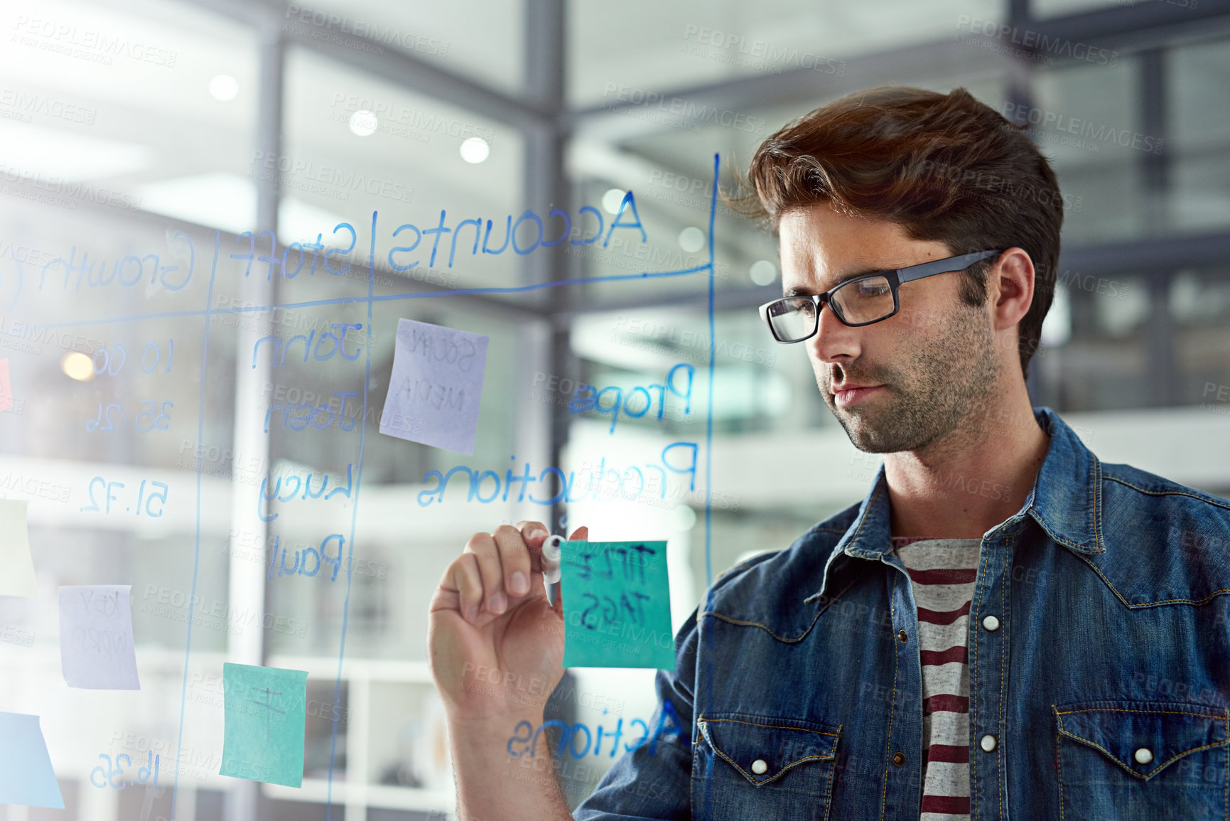 Buy stock photo Cropped shot of a young designer writing notes on a glass wall in a modern office