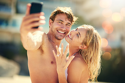 Buy stock photo Cropped shot of a young woman showing off her wedding ring while taking a selfie with her husband
