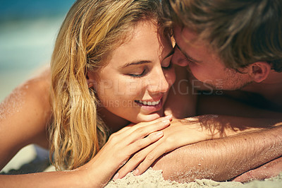Buy stock photo Cropped shot of an affectionate young couple lying on the beach