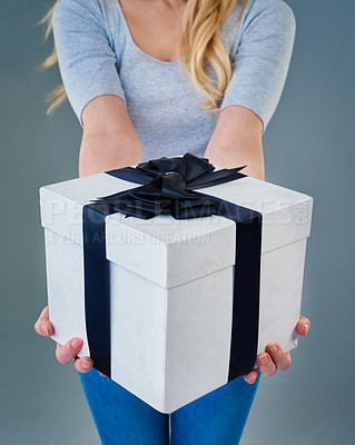 Buy stock photo Cropped studio shot of a young woman holding out a present wrapped with a bow