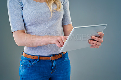Buy stock photo Cropped studio shot of a young woman using her tablet