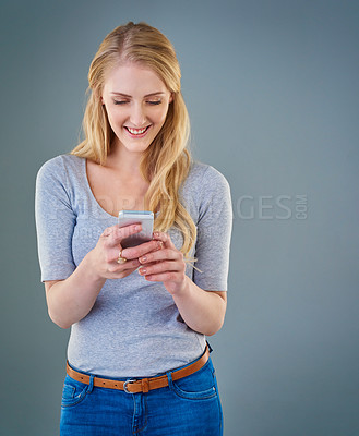Buy stock photo Cropped studio shot of a young woman looking at her smartphone