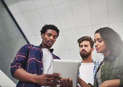 Buy stock photo Cropped shot of three young designers working on a digital tablet in a modern office