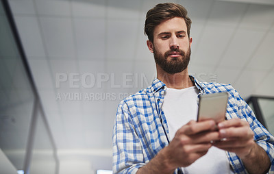 Buy stock photo Cropped shot of a young designer using a cellphone in a modern office