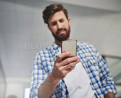Buy stock photo Cropped shot of a young designer using a cellphone in a modern office