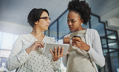 Buy stock photo Low angle shot of two businesswomen looking at a tablet in the office