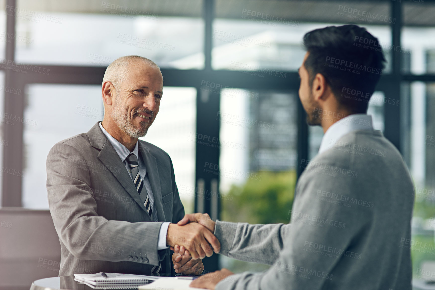 Buy stock photo Cropped shot of two businessmen shaking hands in an office