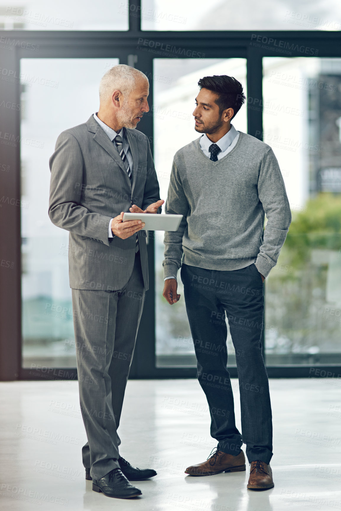 Buy stock photo Full length shot of two businessmen looking at a digital tablet in their office