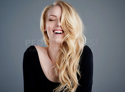 Buy stock photo Studio portrait of an attractive young woman with beautiful long blonde hair laughing against a gray background