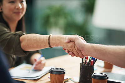 Buy stock photo Cropped shot of two creative businesspeople shaking hands over the table