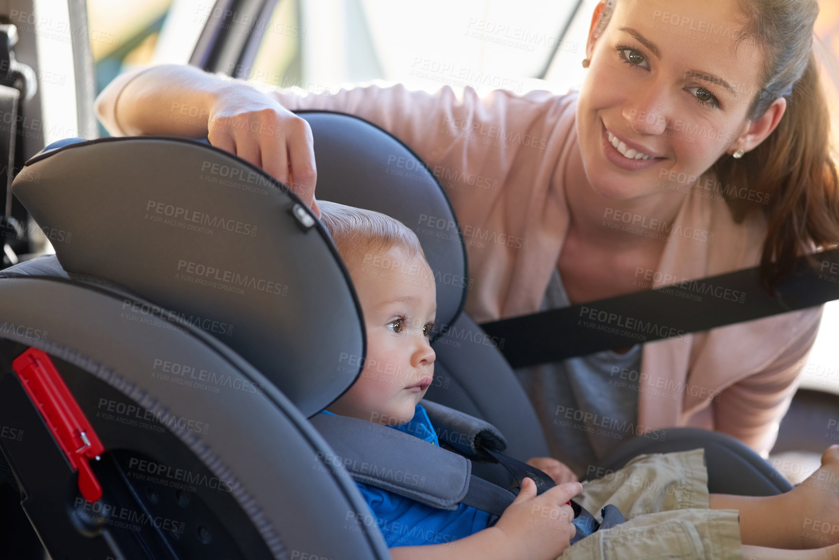 Buy stock photo Portrait of a mother fastening her baby boy safely in a car seat