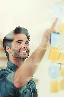 Buy stock photo Cropped shot of a young creative looking at notes on a glass wall in a modern office
