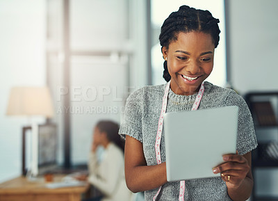 Buy stock photo Shot of a fashion designer looking at something on her tablet