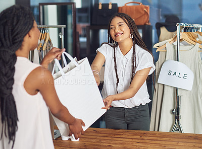 Buy stock photo Cropped shot of a cashier passing on a shopping bag to a customer