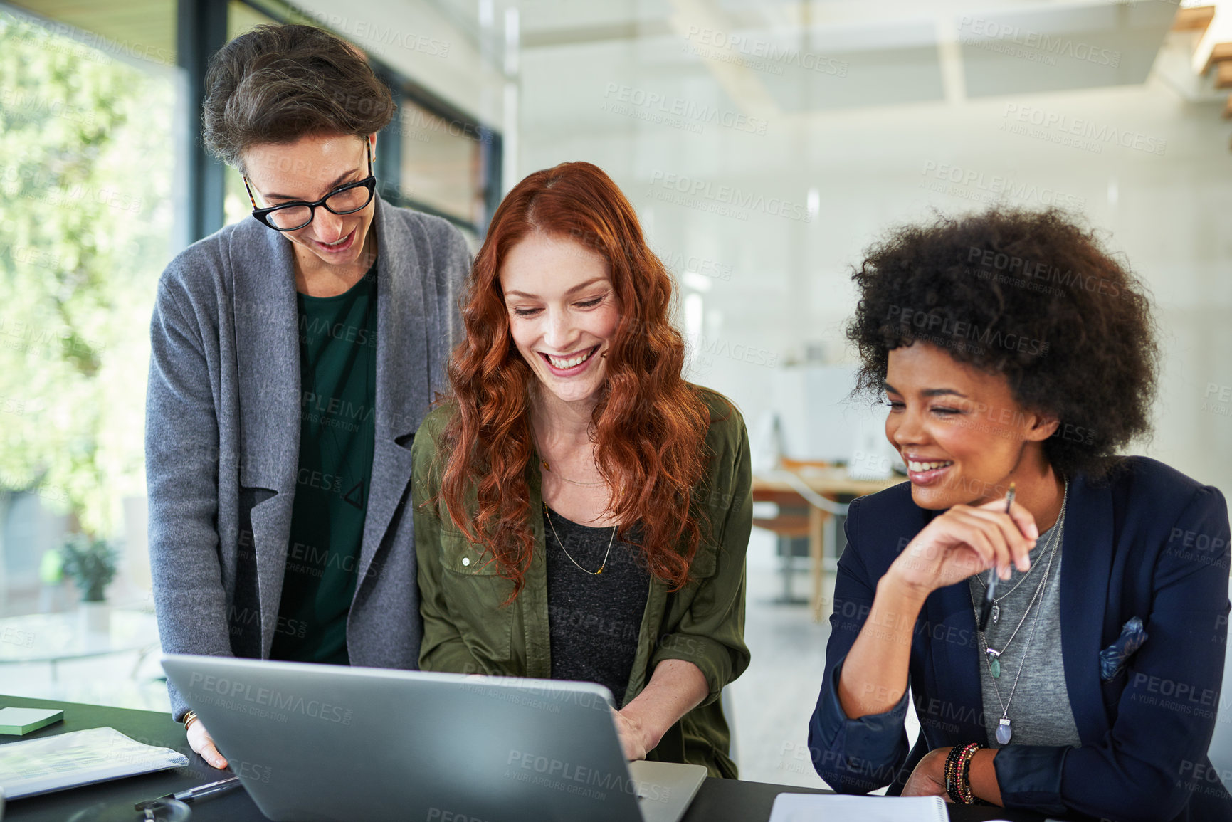 Buy stock photo Cropped shot of three young creatives working together on a laptop in a modern office