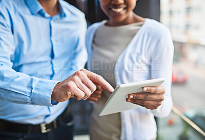 Buy stock photo Cropped shot of two unrecognizable coworkers using a digital tablet while standing on a balcony